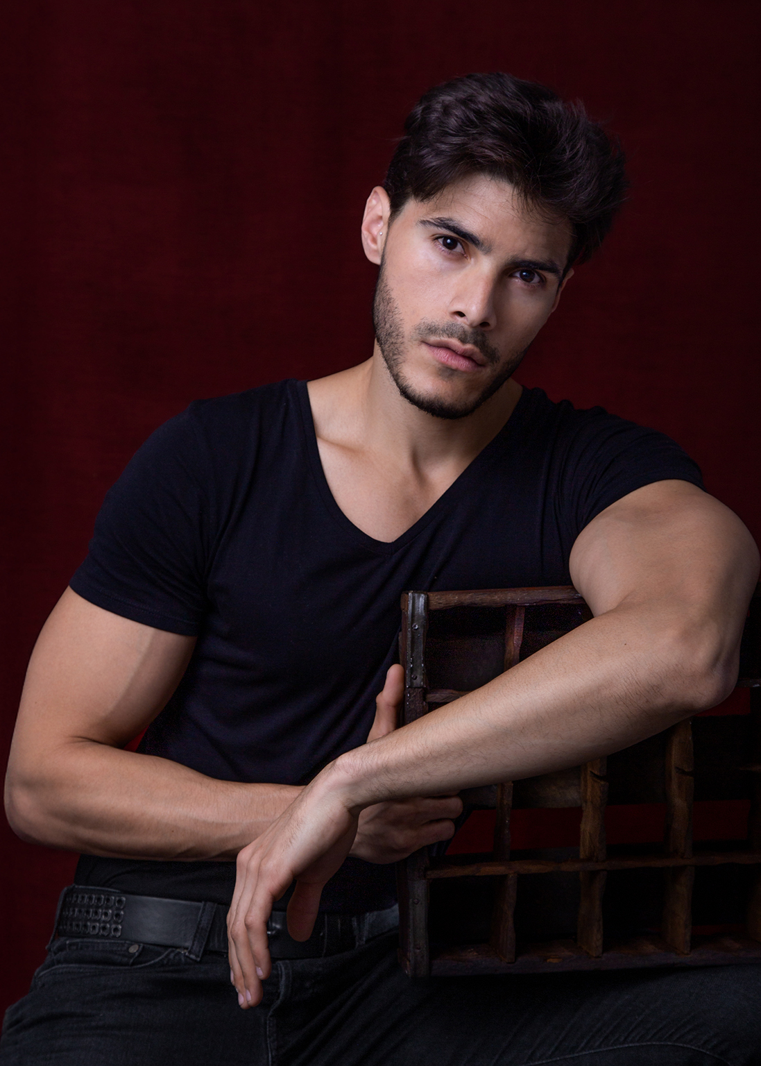 actor venezolano camisa negra viendo a cámara sentado en silla de madera