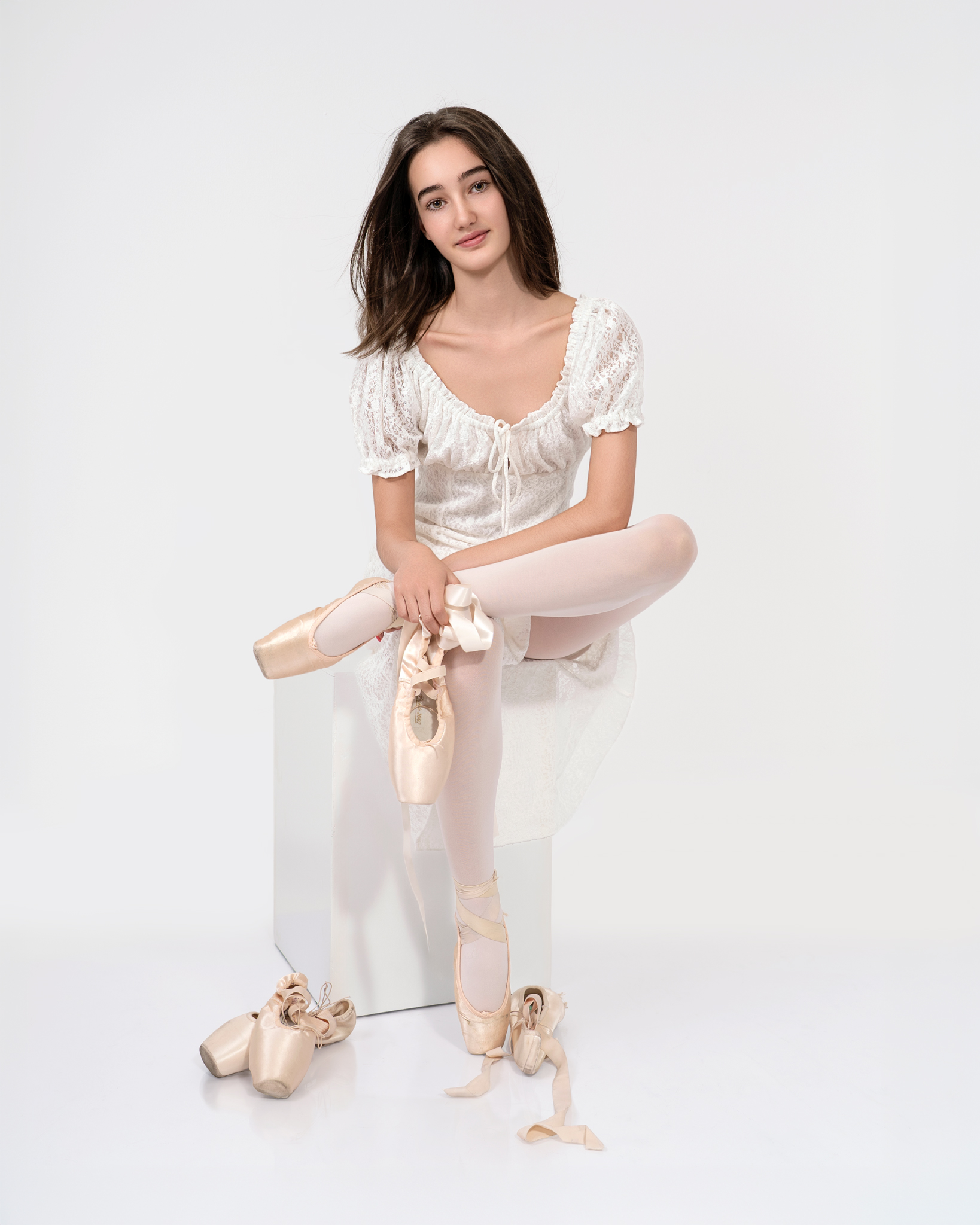 Balletista de blanco sentada en descanso con fondo blanco